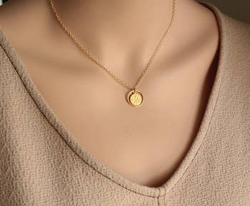 Gold necklace with a round pendant on a mannequin, suitable for elegant attire. Perfect for a minimalist jewelry addition