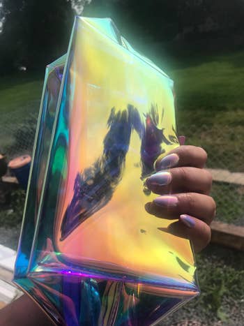 A reviewer holding the holographic makeup bag