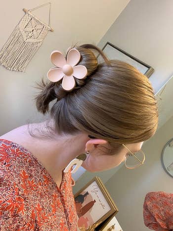 Person with a sleek bun hairstyle adorned with a large flower hair clip