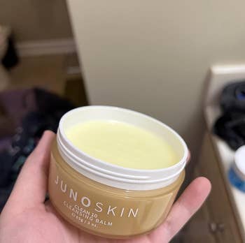 The reviewer holding up a jar of cleansing balm