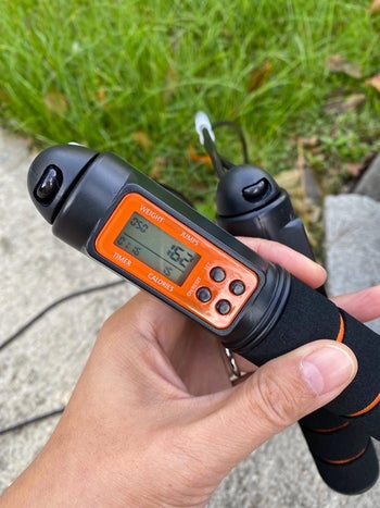reviewer holds black and orange digital jump rope with jump counter