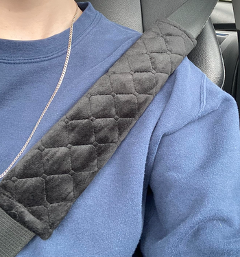 Reviewer wearing a seatbelt with a black soft cross hatch stitched pad wrapped around it where it hits their shoulder