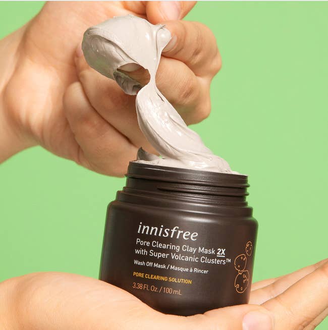Brown container of light brown clay mask in model's hands