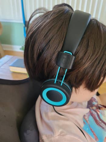 A child wearing the black and blue headphones