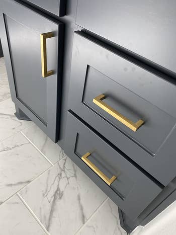Close-up of reviewers gold handles on bathroom cabinets