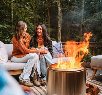 couple sitting on outdoor sofa with fire going on porch