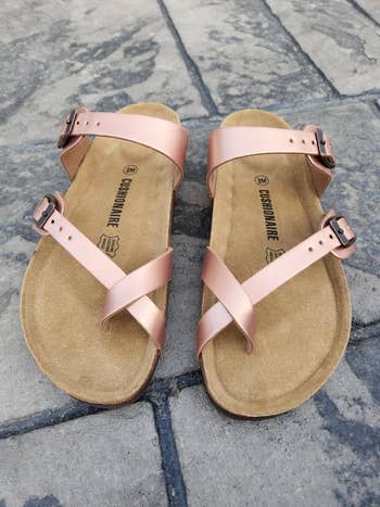 Pair of strappy sandals with metallic buckles connected a chromatic pavement