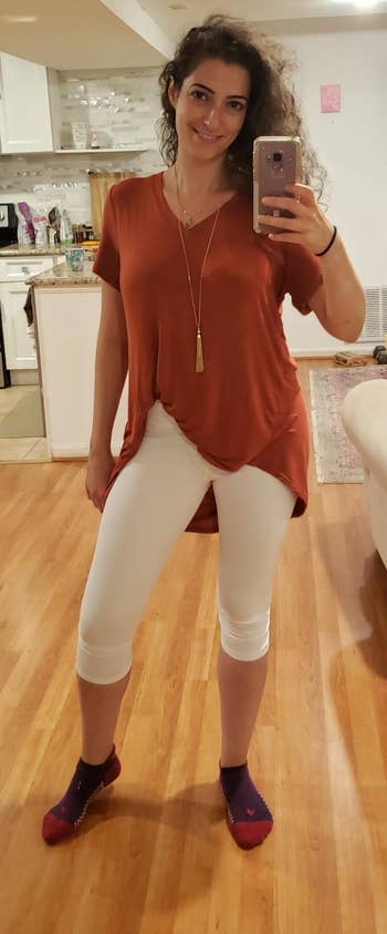 reviewer wearing white leggings with a burnt orange tunic