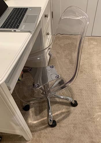 a reviewer photo of the chair in clear in front of a desk 