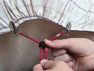 A person adjusting the bedsheet suspenders