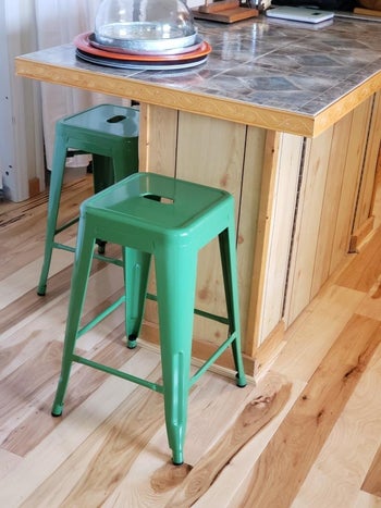 green metal stools by a counter