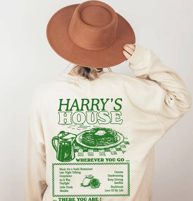 model wearing the beige sweatshirt and showing the back with a 'Harry's House