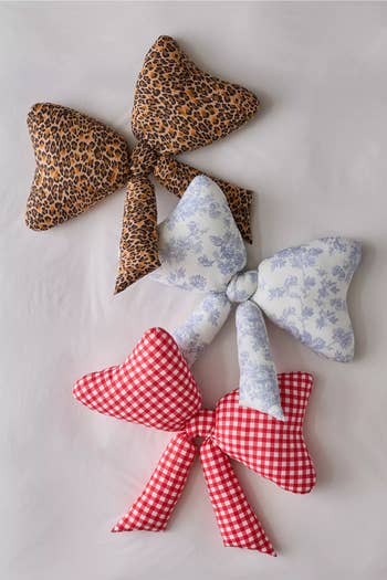 Three decorative heart-shaped hair bows: one leopard print, one with blue floral patterns, and one in red gingham