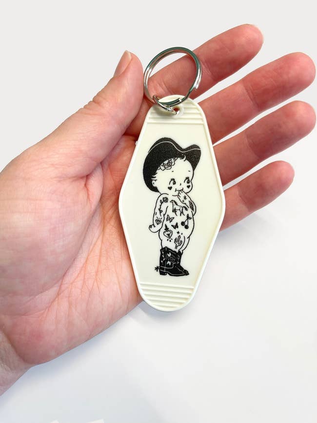 Hand holding a keychain with a cartoon character in a traditional outfit