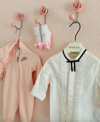 baby outfits hanging from pink rose hooks 
