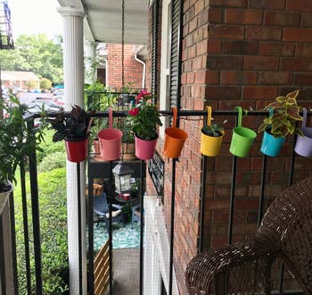 Assorted colorful planters hung on balcony railing, offering apartment gardening ideas