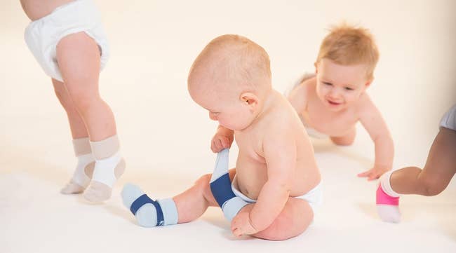 Three babies in diapers and baby socks, two crawling and one sitting