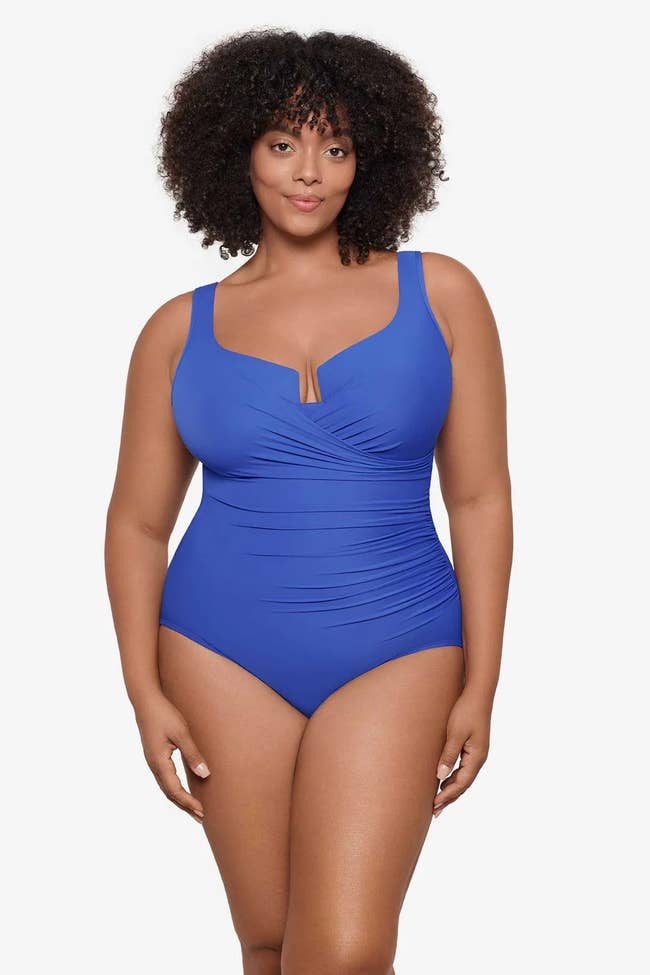 Model wearing a stylish one-piece swimsuit with a gathered wrap design, showcasing swimwear fashion