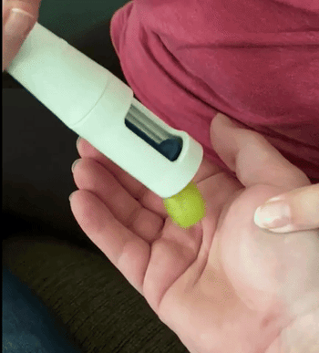 GIF of reviewer using grape cutter to cut a grape into quarters