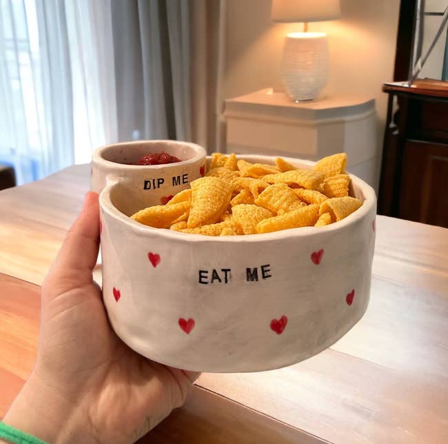 Hand holding a ceramic vessel  acceptable   labeled 