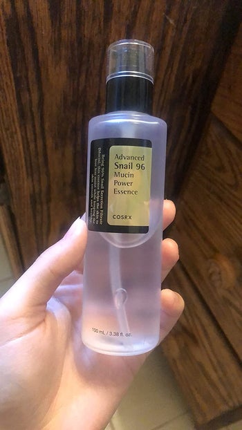 reviewer holding the bottle of snail mucin