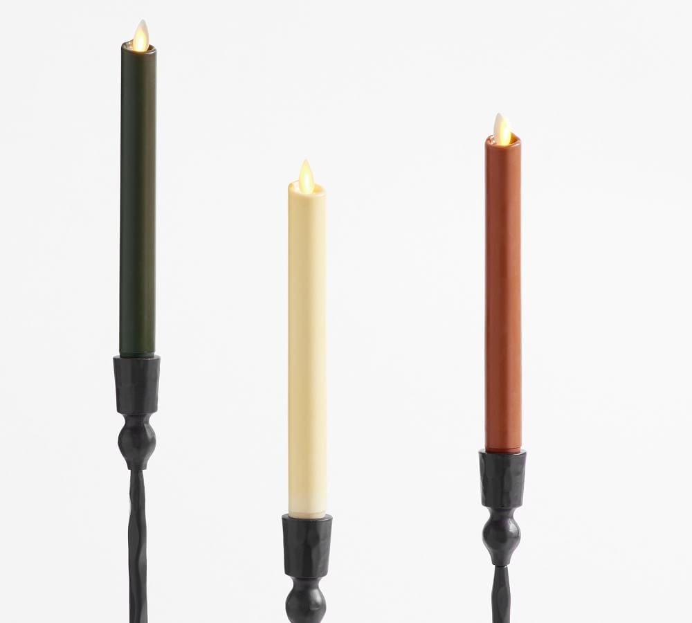 Three taper flameless candles in black, white, and red inside black candle holders on a white background