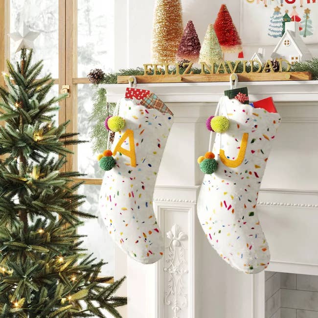 two white stockings with sprinkles of color throughout, a yellow A on one and a yellow J on the other
