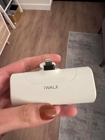 Person holding a portable iWALK charger compatible with a smartphone