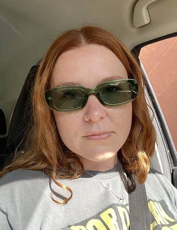 reviewer wearing sunglasses in green color while sitting in car