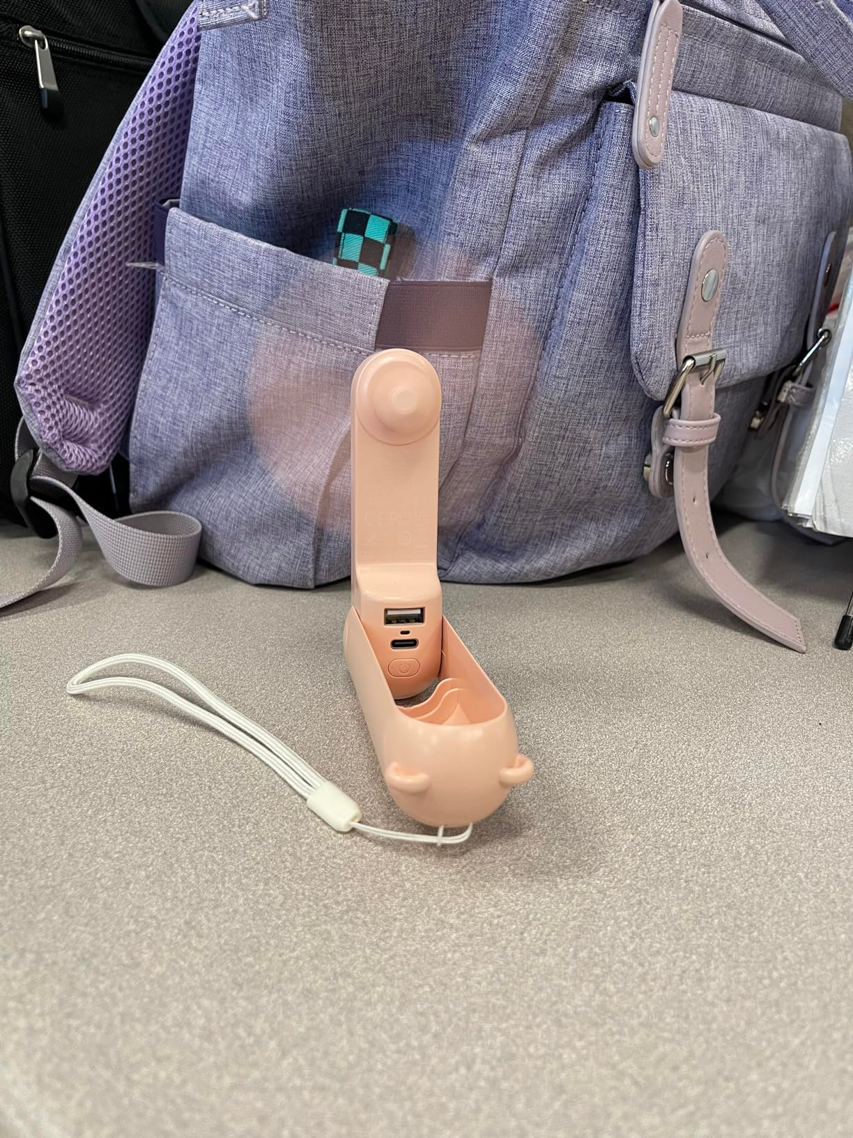 Mini fan folded at a 90 degree angle and standing upright on a surface for hands free cooling