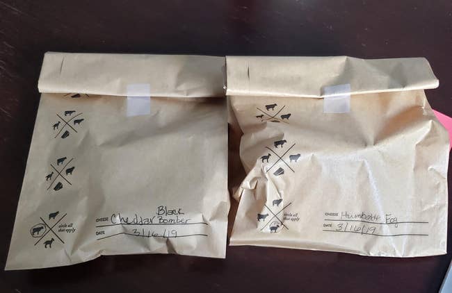 a reviewer photo of two storage bags each labeled with a date and the type of cheese inside 