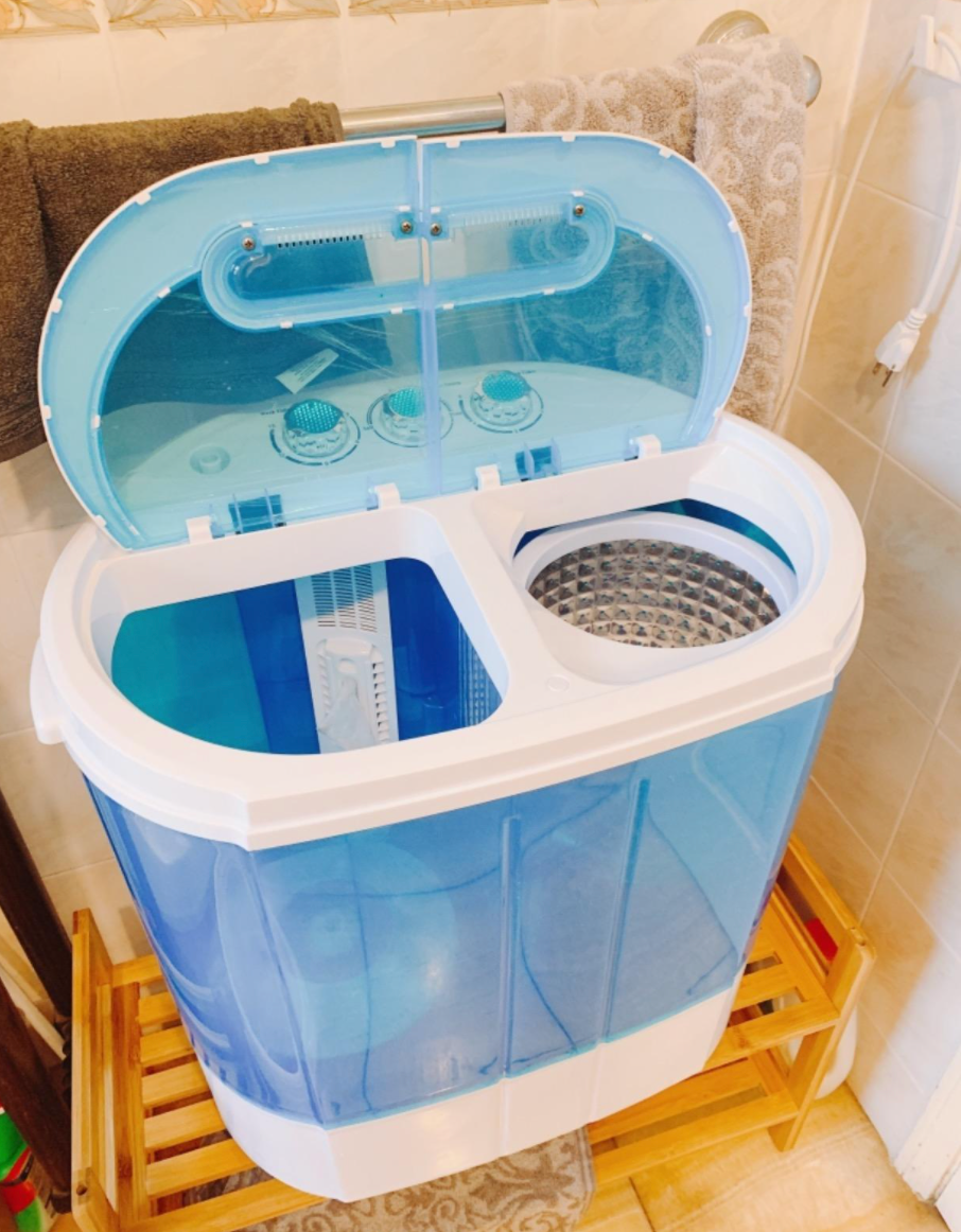A small blue washing tub with two sides  and a lid with controls on the top 