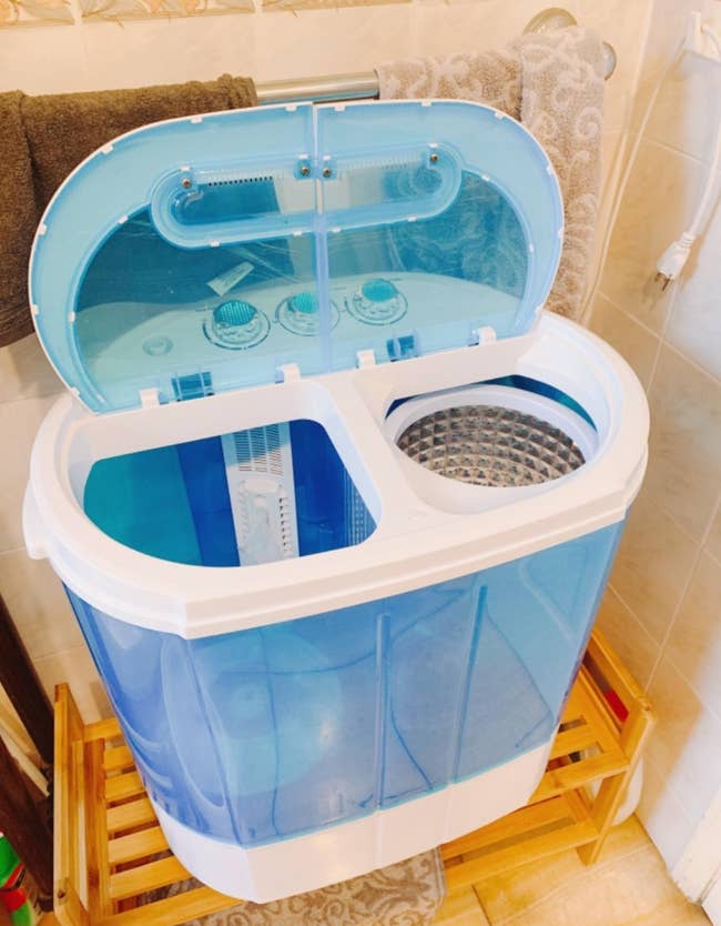 A small blue washing tub with two sides  and a lid with controls on the top 