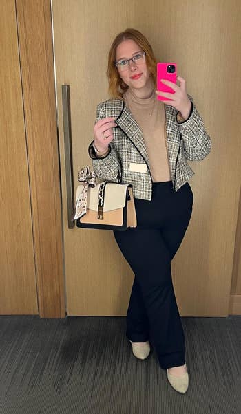 Woman in blazer and slacks posing with a handbag for a shopping article