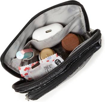 Open black toiletry bag with various personal care items inside, including a toothbrush and small bottles
