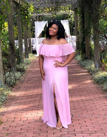 a reviewer in an off-shoulder ruffled pink gown with a leg slit, posing outdoors