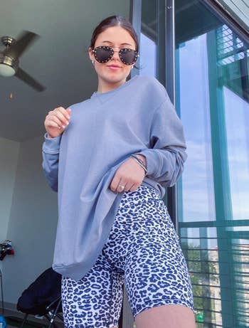 reviewer wearing the white leopard print bike shorts with an oversized gray sweatshirt