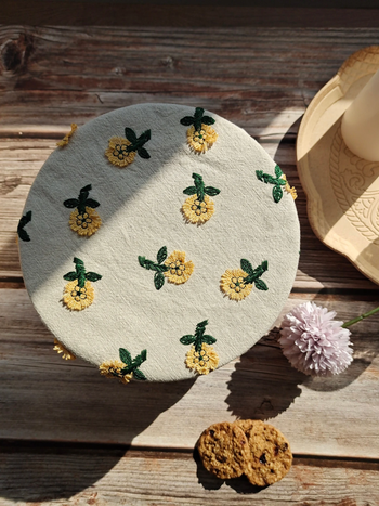A cotton off white bowl cover with embroidered yellow flowers 