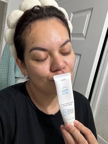 a reviewer kissing the vessel  of moisturizer