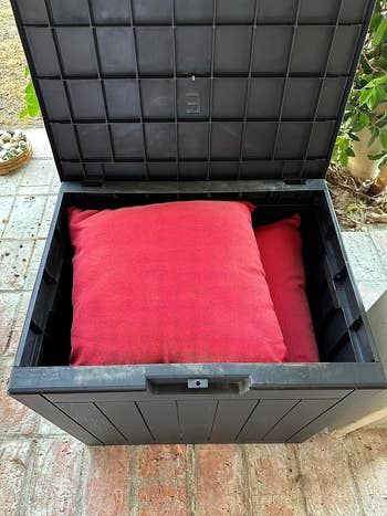reviewer opening outdoor storage box to reveal red pillows