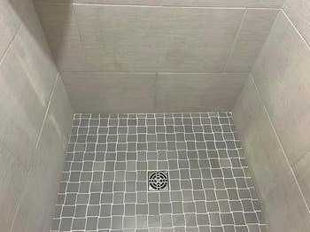 Tiled shower floor with small square tiles and a central drain, showcasing modern bathroom design