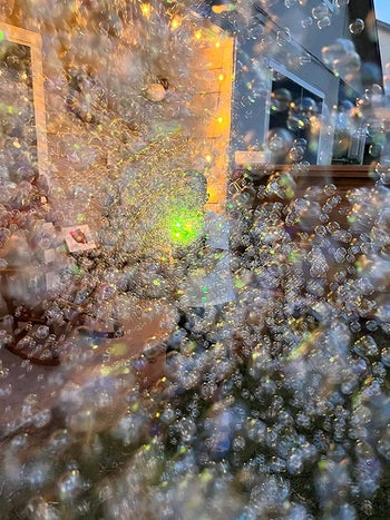 reviewer photo of lots of bubbles in their backyard from the bubble gun