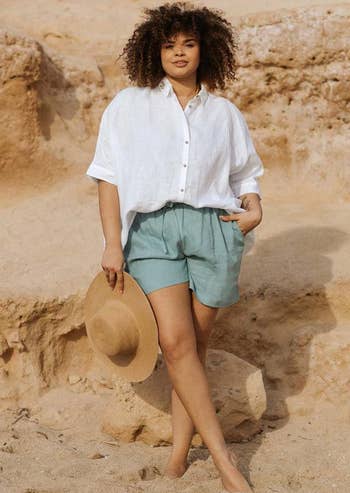 model wearing the teal shorts with a white button down