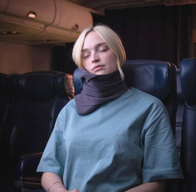 model sleeping in an airplane seat while using the pillow