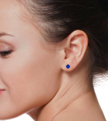 a model wearing blue sapphire stud earrings