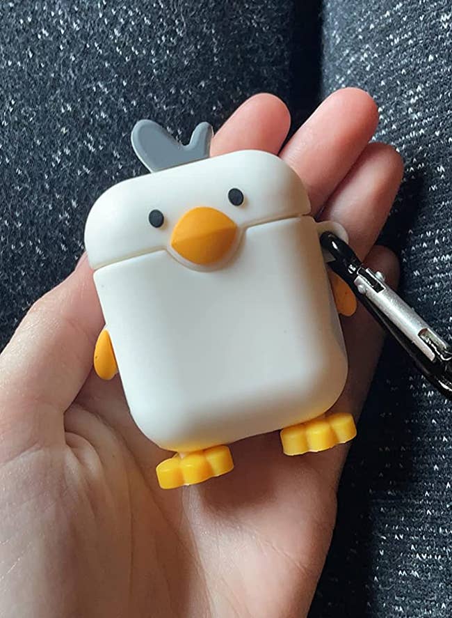 reviewer holding white gray and yellow case with chicken face beak wings and feet