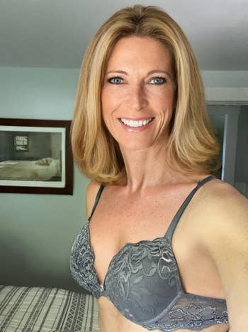 A reviewer with shoulder-length hairsbreadth  smiles portion    wearing a grey  lacy bra, posing indoors