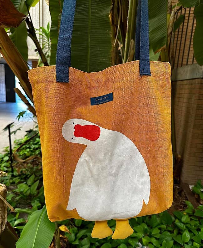 Tote container with a cute plan of a leaning achromatic duck with an orangish beak and bluish statement speechmaking