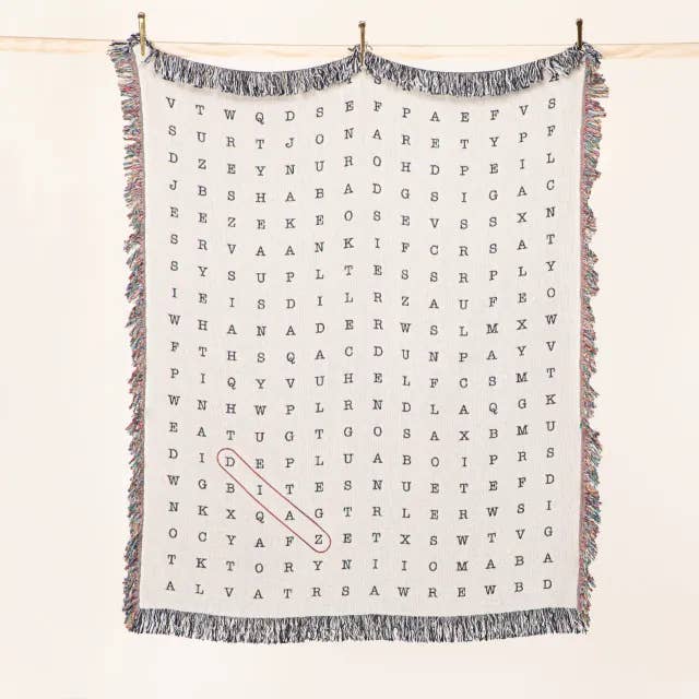 Word search puzzle blanket hanging on a rod with fringe edges for a fun decor piece