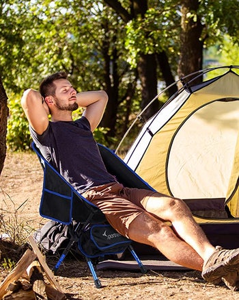 model lounging in the camper chair in a forest